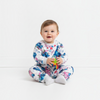 Twinkles baby wearing a white thermal pajama set with Stitch and Angel print, sitting on a white floor.