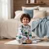 Twinkles Avengers print long-sleeve pajama set worn by a young boy sitting on a rug in a cozy bedroom