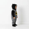 Twinkles baby wearing a grey and black fleece Batman romper with a hooded cape and yellow logo, side view