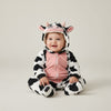 Twinkles baby wearing a cozy cow-print polar fleece hooded bunting with pink chest panel and cute cow ears