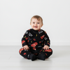 Twinkles baby wearing a black fleece pajama set featuring Lightning McQueen car prints and yellow lightning bolts