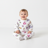 A smiling baby wearing a Twinkles My Little Pony fleece pajama set with colorful character prints on white fabric.