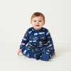 Twinkles baby wearing a blue fleece Tom and Jerry pajama set with long sleeves and footed pants on a white background