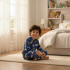 Twinkles blue Tom and Jerry fleece pajama set worn by a smiling boy sitting on a bedroom rug